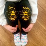 Toddler sitting wearing black bees knees pants with yellow bees
