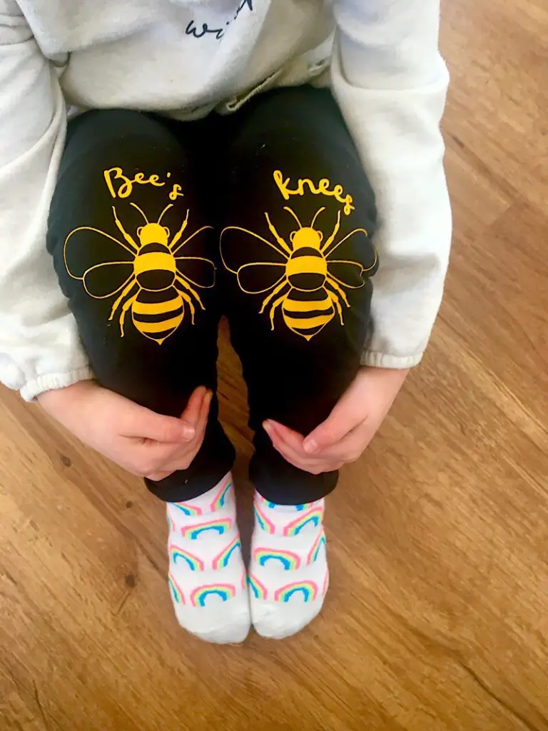 Toddler sitting wearing black bees knees pants with yellow bees