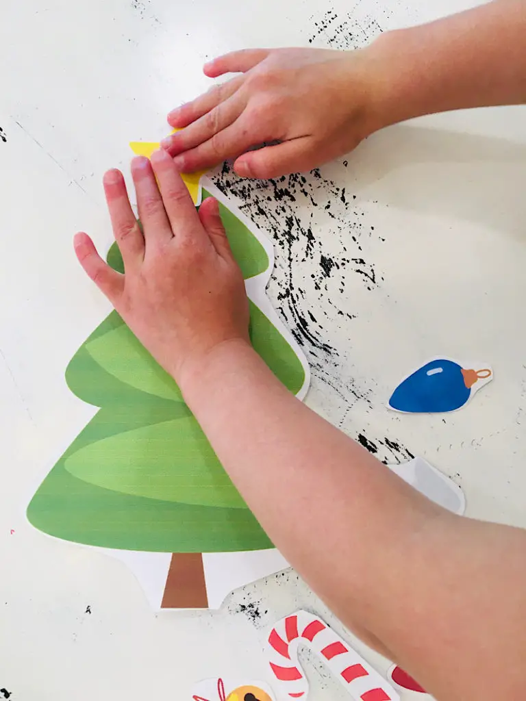 Toddler hands gluing a star on a paper christmas tree