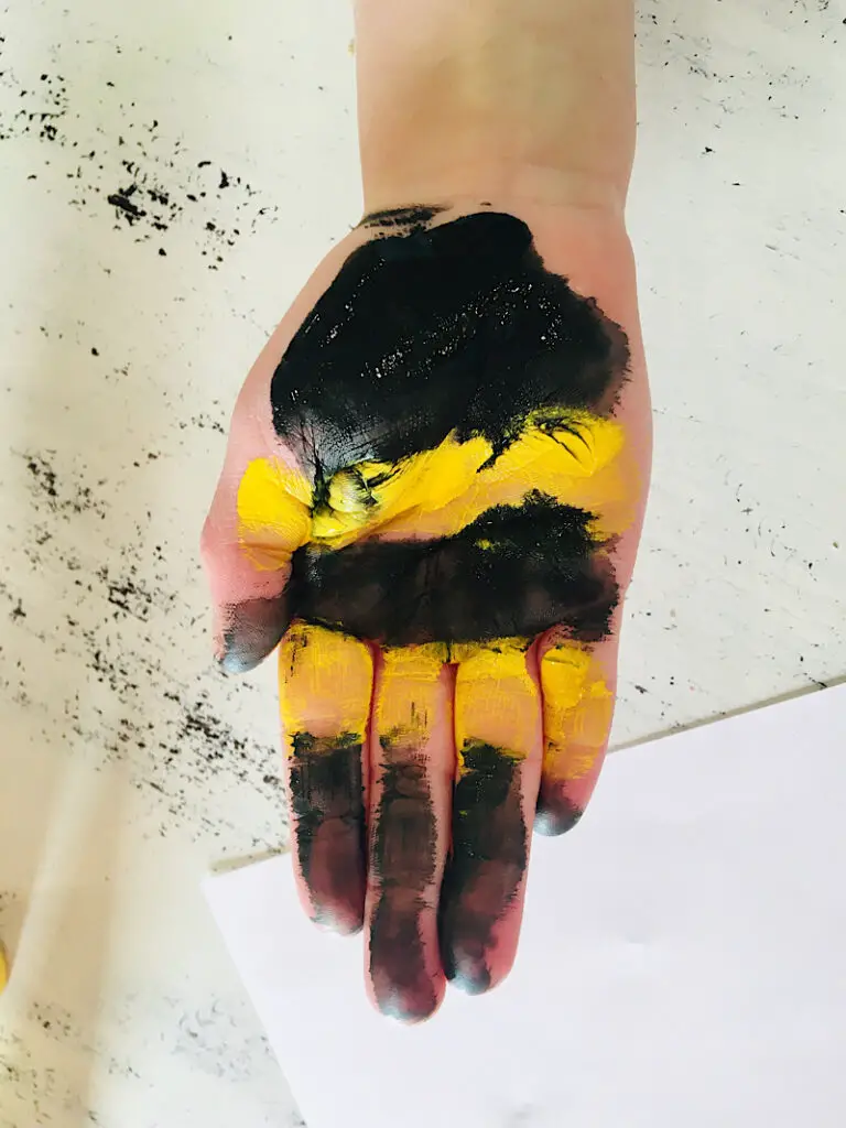 child's hand painted with stripes to make a handprint bumblebee