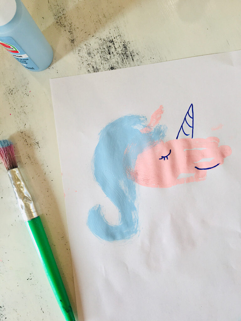 Painting blue hair on the unicorn handprint